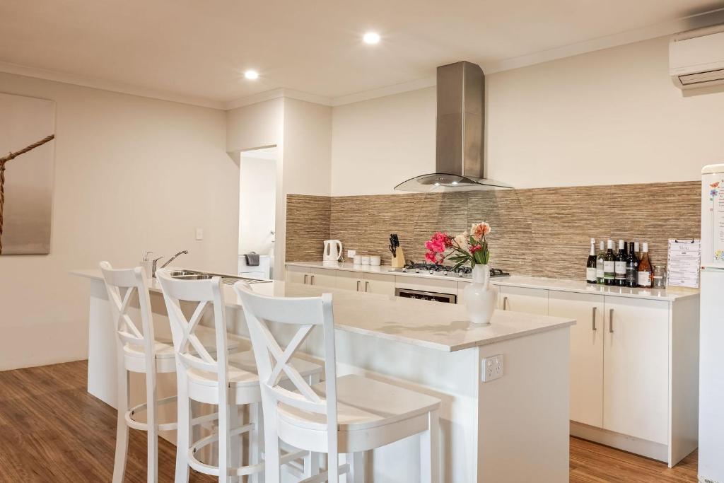 a kitchen with white cabinets and a counter with white stools at Villa 16 @ Rivendell Winery Estate - Yallingup in Yallingup Siding