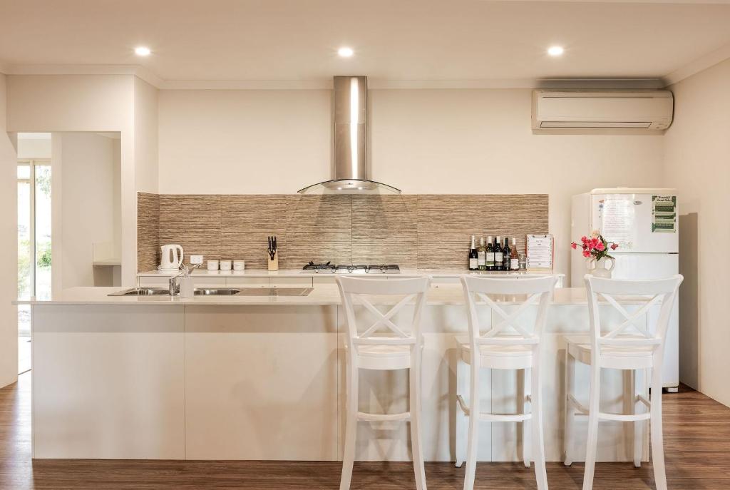 a kitchen with white counters and white stools at Villa 16 @ Rivendell Winery Estate - Yallingup in Yallingup Siding