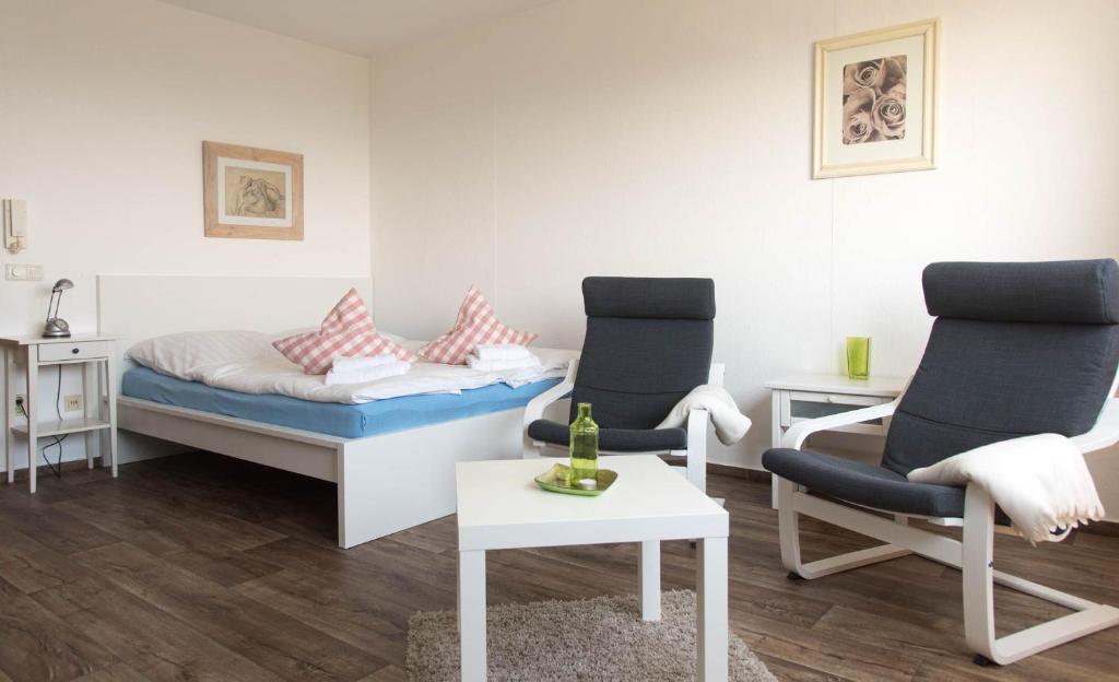 Zimmer mit 2 Stühlen, einem Bett und einem Tisch in der Unterkunft Ferienwohnung Kleine Möwe in Schilksee