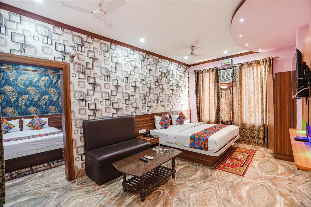 a bedroom with a bed and a couch and a table at FabHotel Deepak Palace in Varanasi