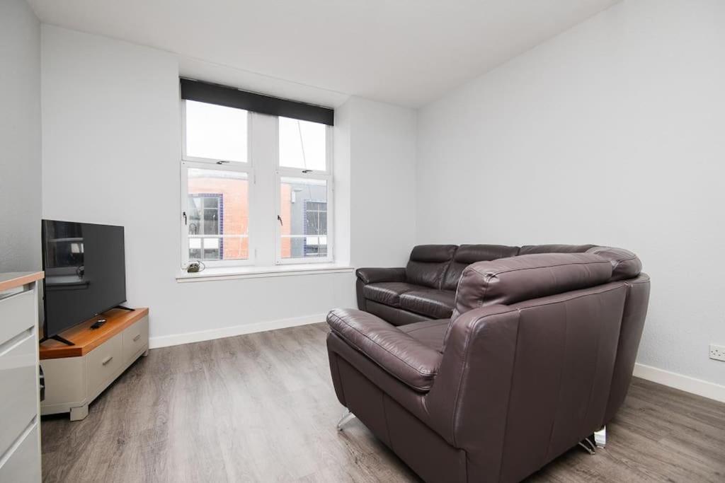 a living room with a leather couch and a television at Bright beautiful flat in Dundee in Dundee