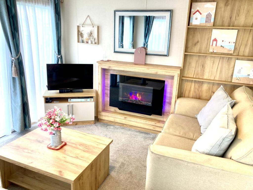 a living room with a couch and a fireplace at 102, Duckpool Lodge in Bude