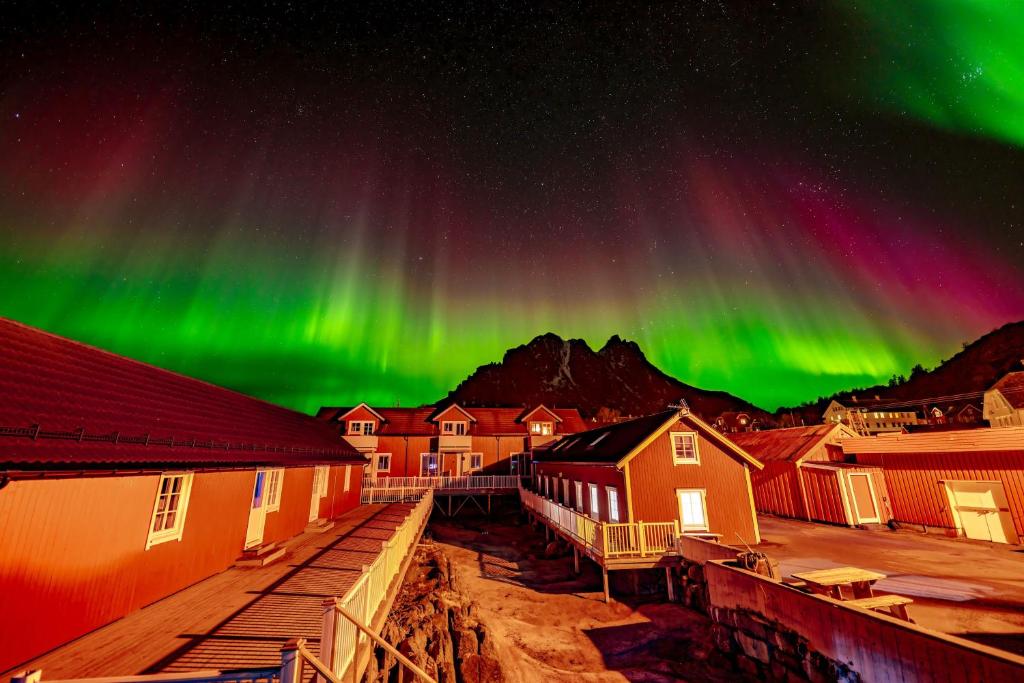 an aurora over a town with buildings and houses at Ure Lodge in Sennesvik