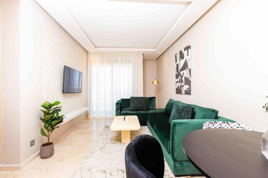 a living room with a green couch and a table at Central Charm: 1-Bed Apartment in Hay Riad in Rabat
