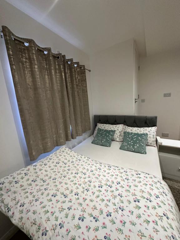 um quarto com uma cama com uma colcha e almofadas florais em Smart Cosy/Small Double Room in Oakridge Road Bromley em Lewisham