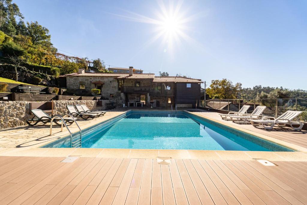 a swimming pool with chairs and a house at Casa do Souto Vieira do Minho - Casa Rural com piscina by House and People in Vieira do Minho