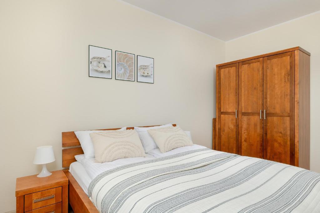a bedroom with a bed and a wooden cabinet at Wilczak Spacious Apartment with FREE GARAGE Poznań by Noclegi Renters in Poznań