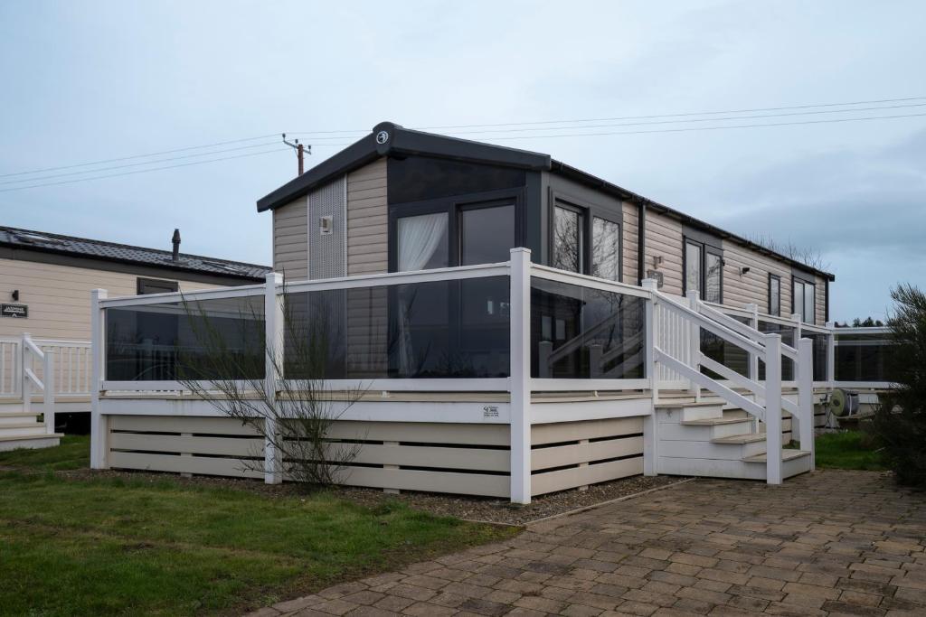 a house with glass doors and a white railing at ELVIS, King Of The Caravans, 6 Berth in Port Seton