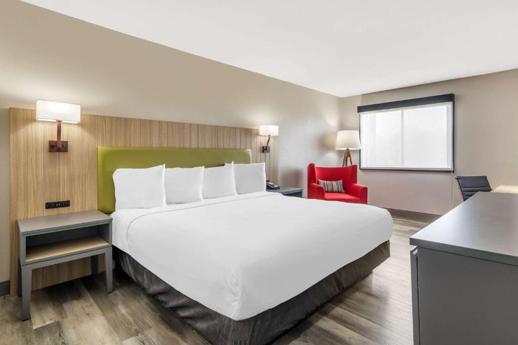 un grande letto bianco in una stanza con una sedia rossa di Country Inn & Suites by Radisson, Atlanta Airport South, GA ad Atlanta