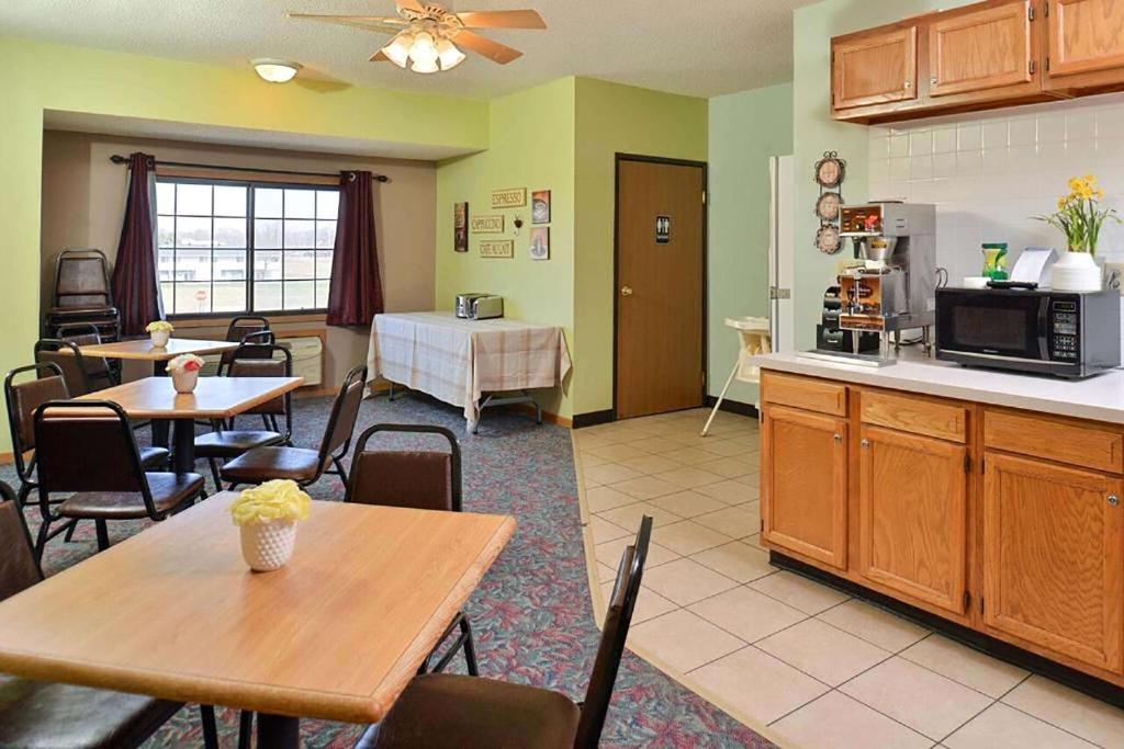 a kitchen and dining room with tables and a counter at Sauk River Inn & Suites, a Travelodge by Wyndham in Sauk Centre