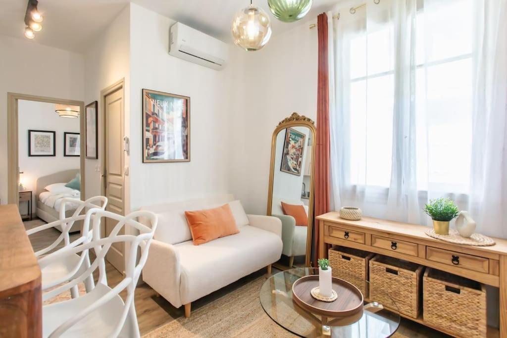 ein Wohnzimmer mit einem weißen Sofa und einem Tisch in der Unterkunft L46 2P Port, 2min du Cap et 5 du port/ CLIM & WIFI in Nizza
