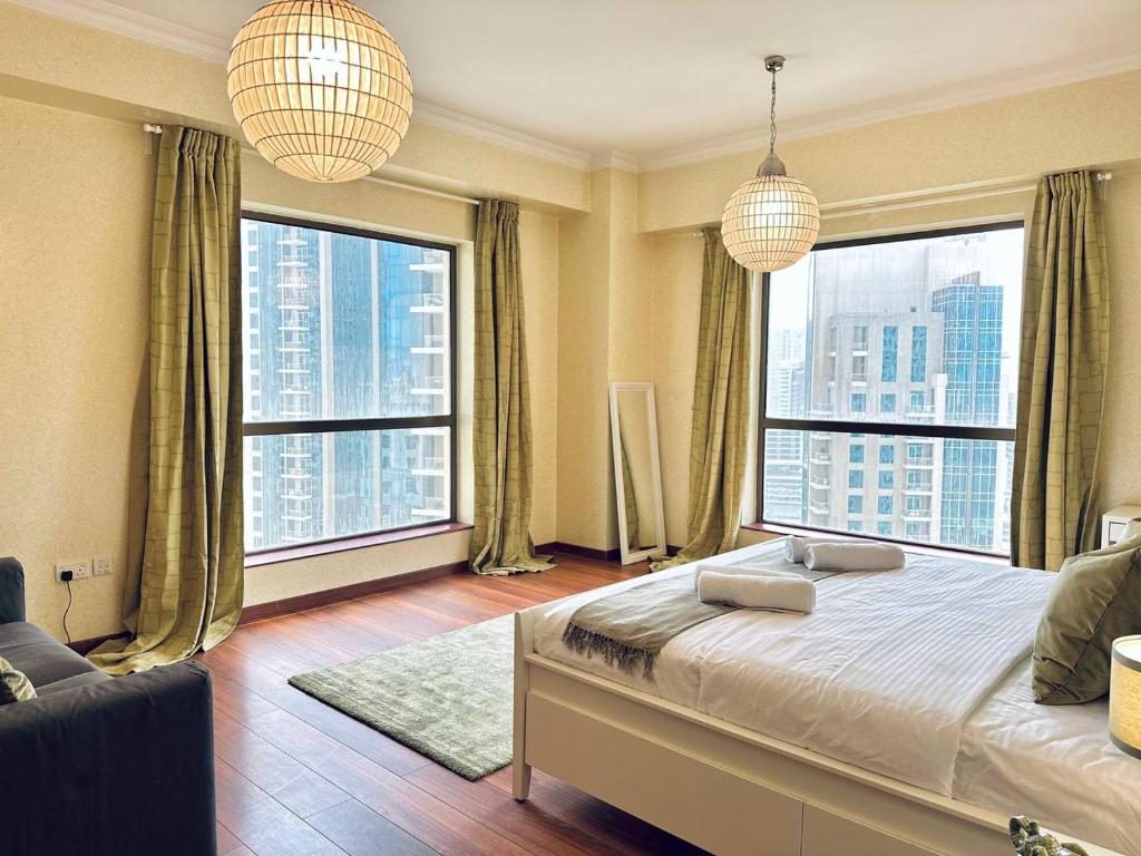 a bedroom with large windows and a bed and a couch at Sunkissed holiday homes Stunning marina view 4BR plus maid room on JBR beach near mall in Dubai