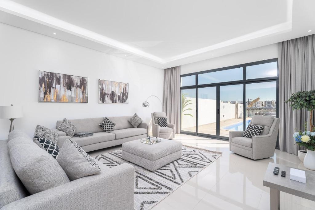 a white living room with a couch and chairs at Nasma Luxury Stays - Luxurious Villa with Private Pool & Beach Access in Fujairah