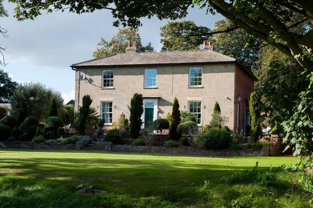 a large brick house with a green lawn at FIRS Sleeps 15 Stunning country house with hot tub in Sudbourne