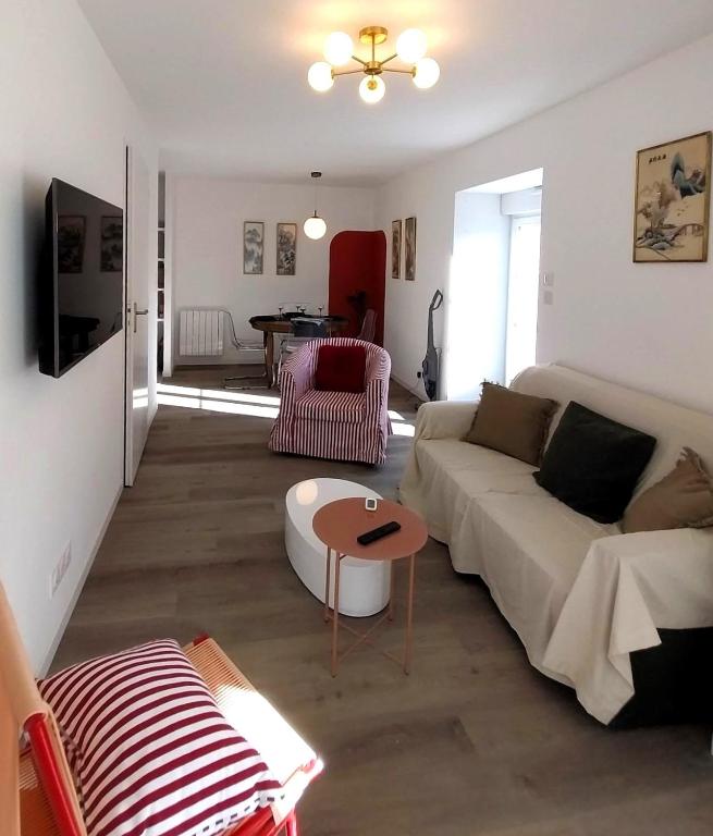 ein Wohnzimmer mit einem Sofa und einem Tisch in der Unterkunft Gîte-appartement RDC La Ville au Monnier in Pleurtuit