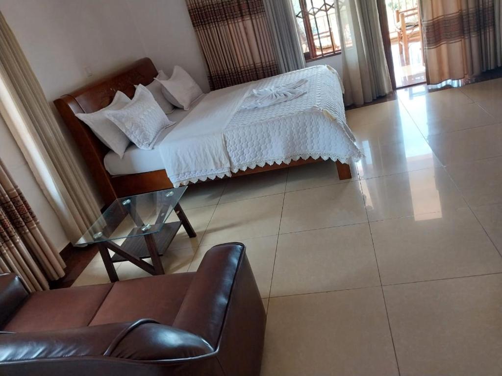 1 dormitorio con 1 cama, 1 silla y 1 sofá en CONVENTION VILLA APART HOTEL, en Kigali