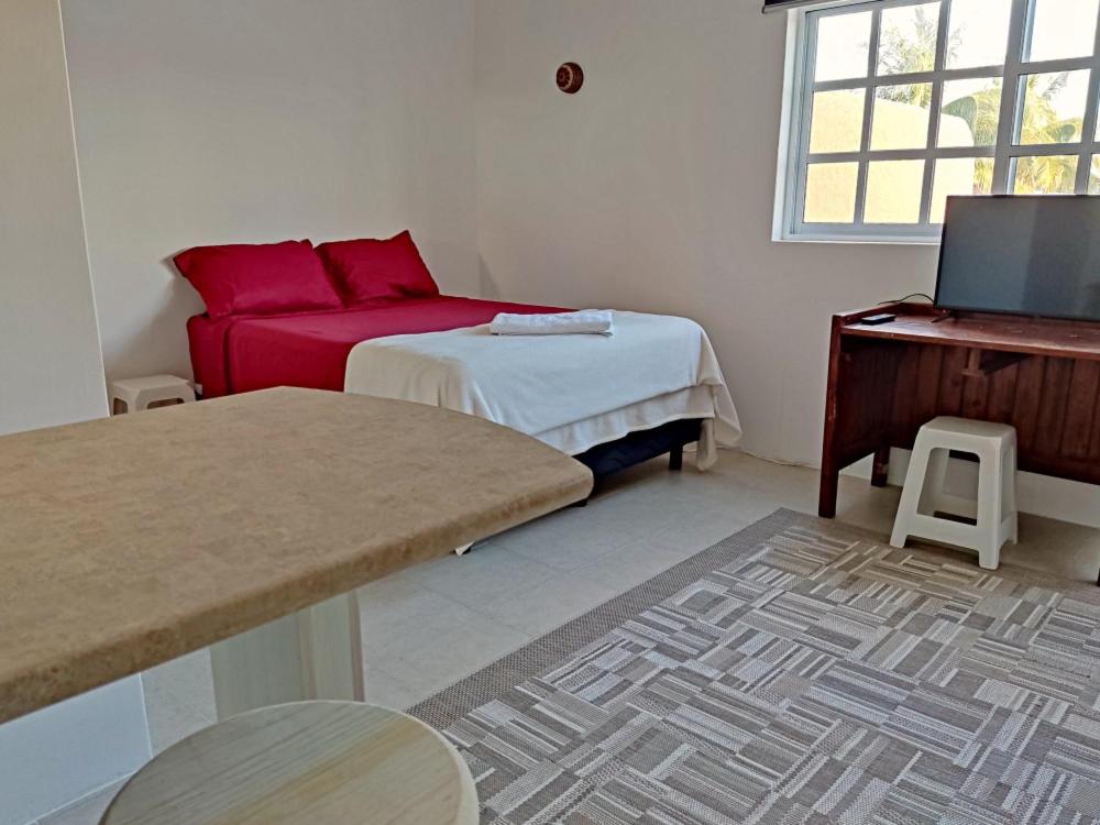 Habitación pequeña con cama y sofá rojo. en Studio Norte, Casa Brisamar, en Puerto Morelos