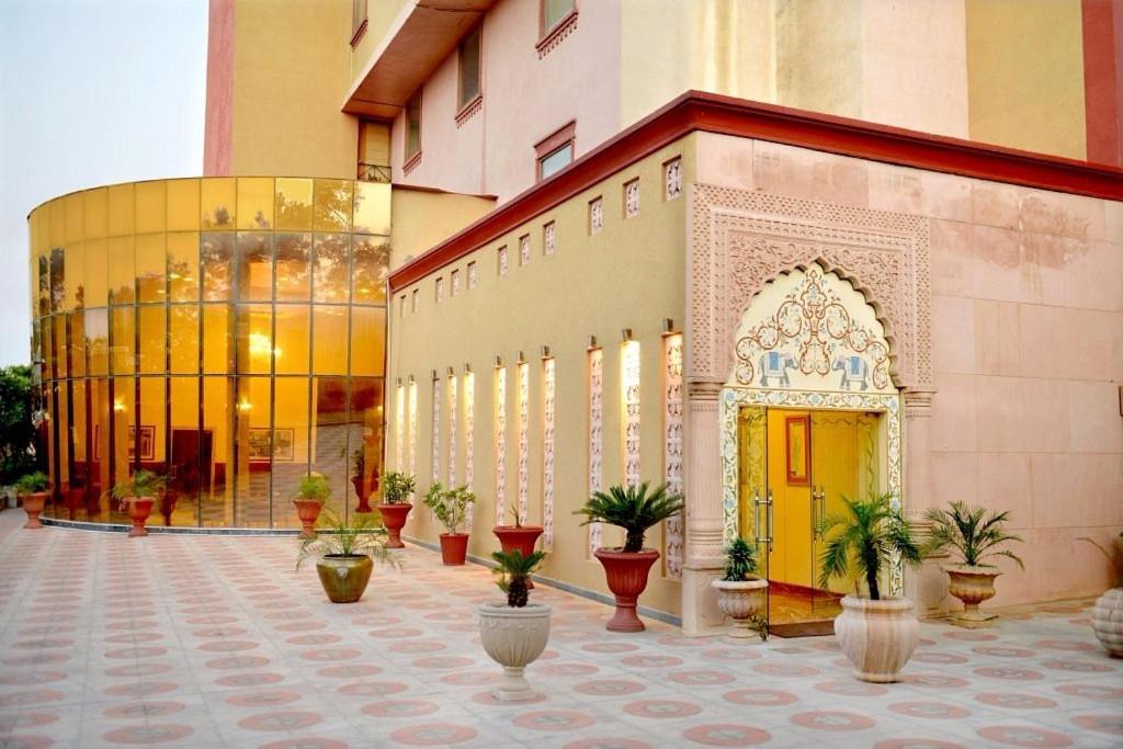 a building with a yellow door and potted plants at Pink Pearl Hotel in Jaipur