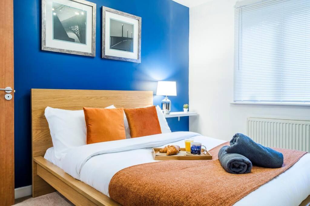 Una cama con almohadas naranjas y una bandeja de comida. en Sapphire Retreat - Central Location - Free Parking, FastWiFi and Smart TV by Yoko Property en Derby