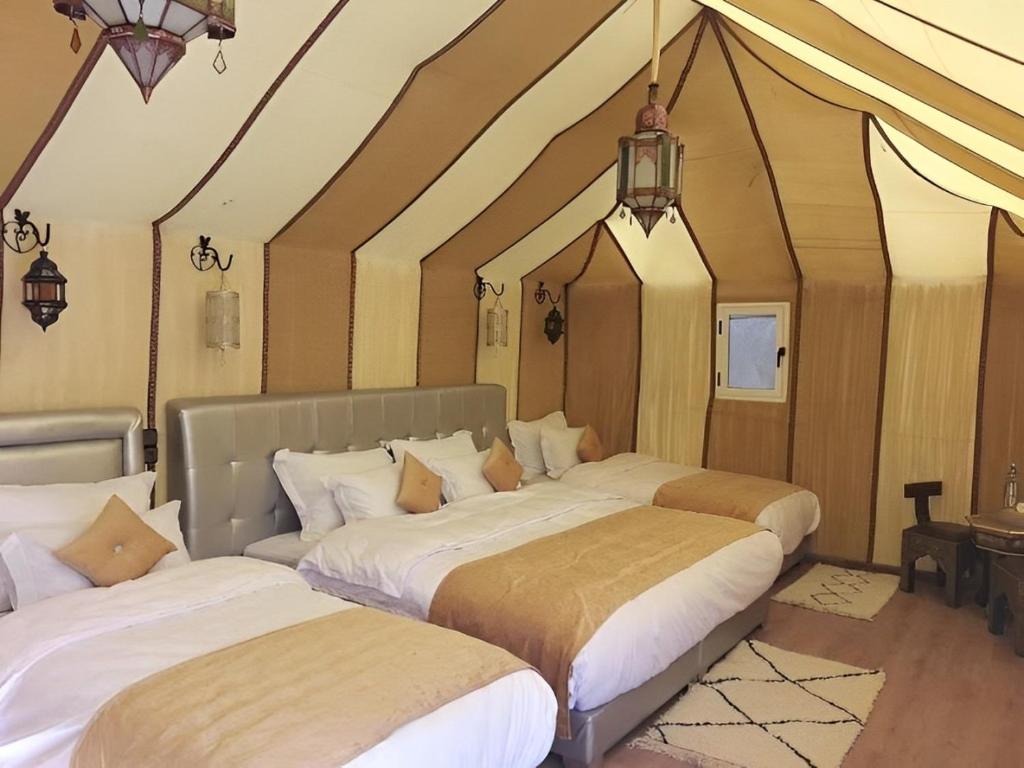 a room with three beds in a room at Exceptional Luxury Camp in Merzouga