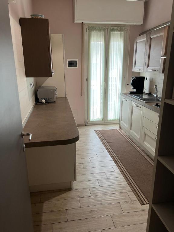 Il comprend une cuisine avec des placards blancs et du parquet. dans l'établissement Appartamento Via Milano Prato, à Prato
