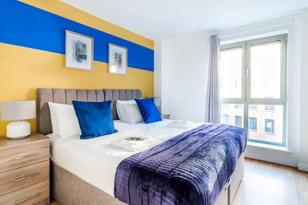 1 dormitorio con 1 cama grande y paredes azules y amarillas en Brook Retreat - City Centre - Free Parking, Fast WiFi and Smart TV by Yoko Property en Derby