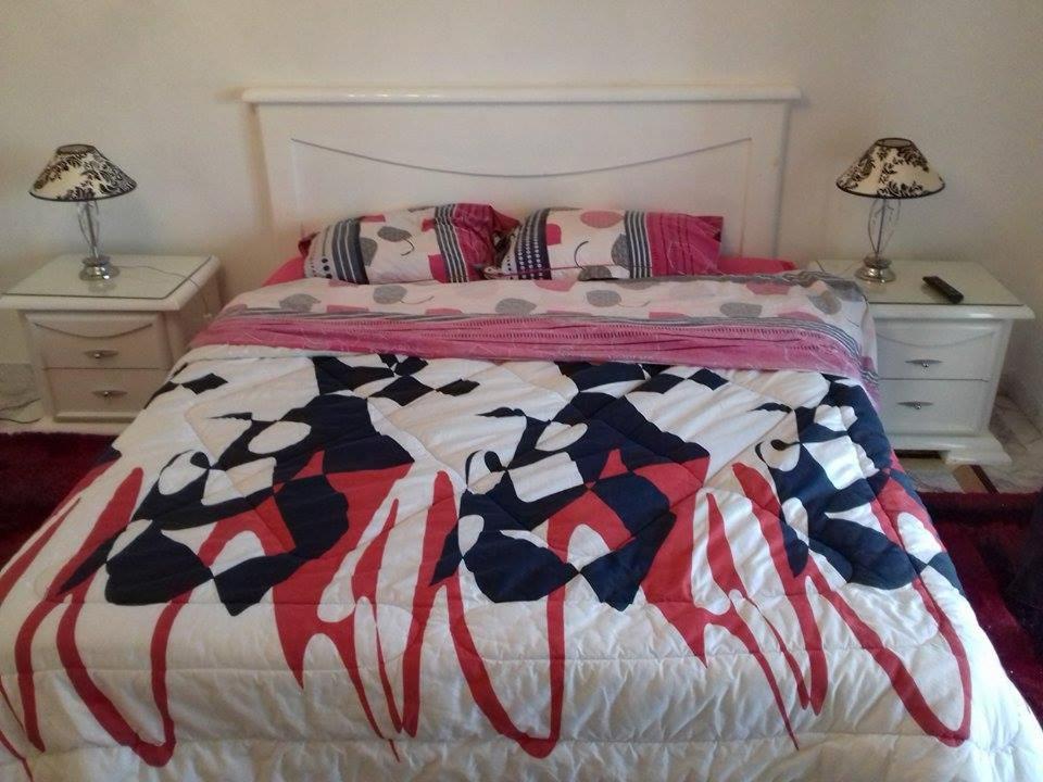 uma cama com um cobertor vermelho branco e azul em Belhassen II em Tunes