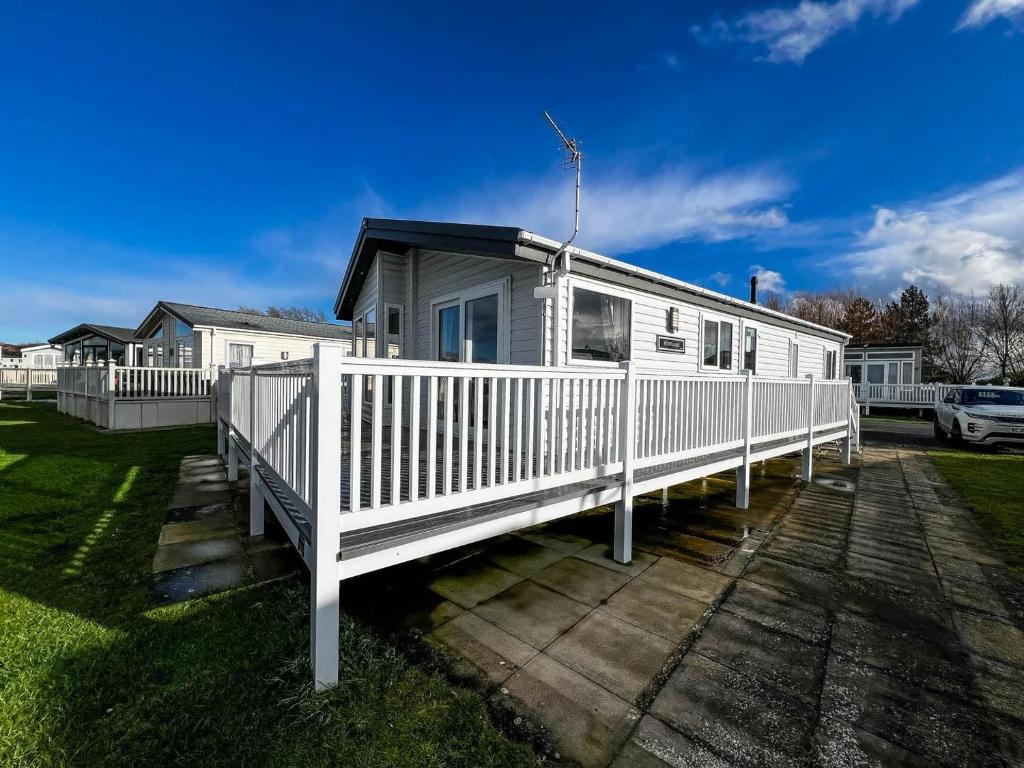 a white mobile home with a porch and a fence at Beautiful Lodge With Decking In Hunstanton At Manor Park Ref 23195k in Hunstanton