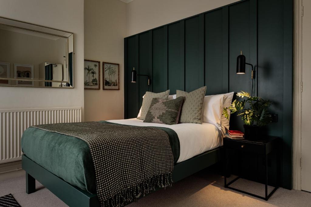 a bedroom with a large bed with a green headboard at Brayford House in Lincoln