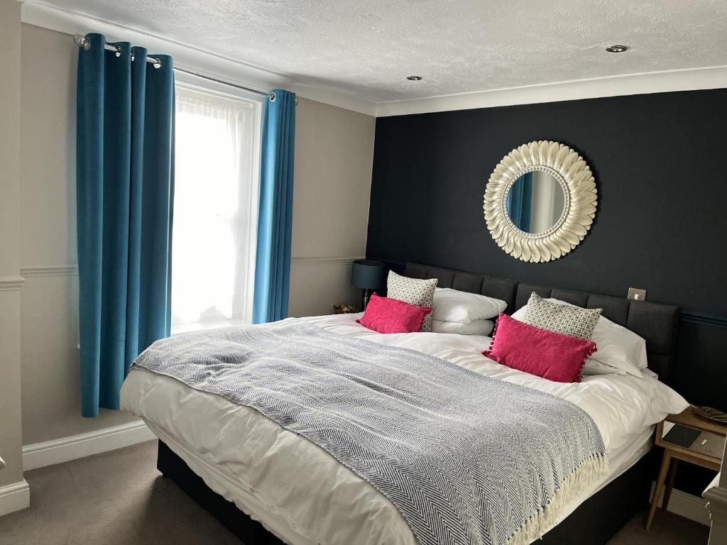 a bedroom with a large bed with red pillows and a mirror at The Ship Hotel in New Romney