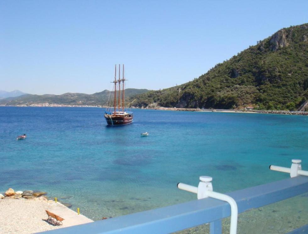 a boat in the water next to a beach at Hotel Avlakia in Kokkari