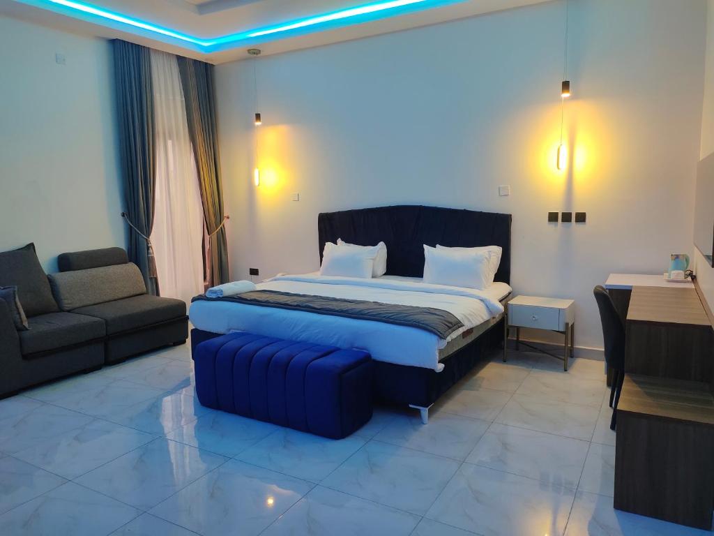 a bedroom with a king sized bed and a couch at Passready Hotel and Suites Nnewi in Nnewi