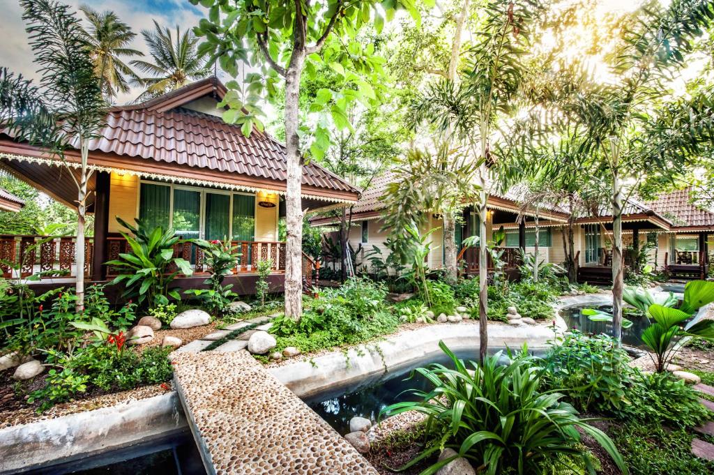 a house with a swimming pool in front of a yard at Baan Nam Pen Resort in Amphawa