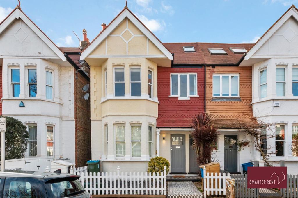a row of houses with a white fence at 3 Bedroom Apartment - Kew Village in Richmond upon Thames