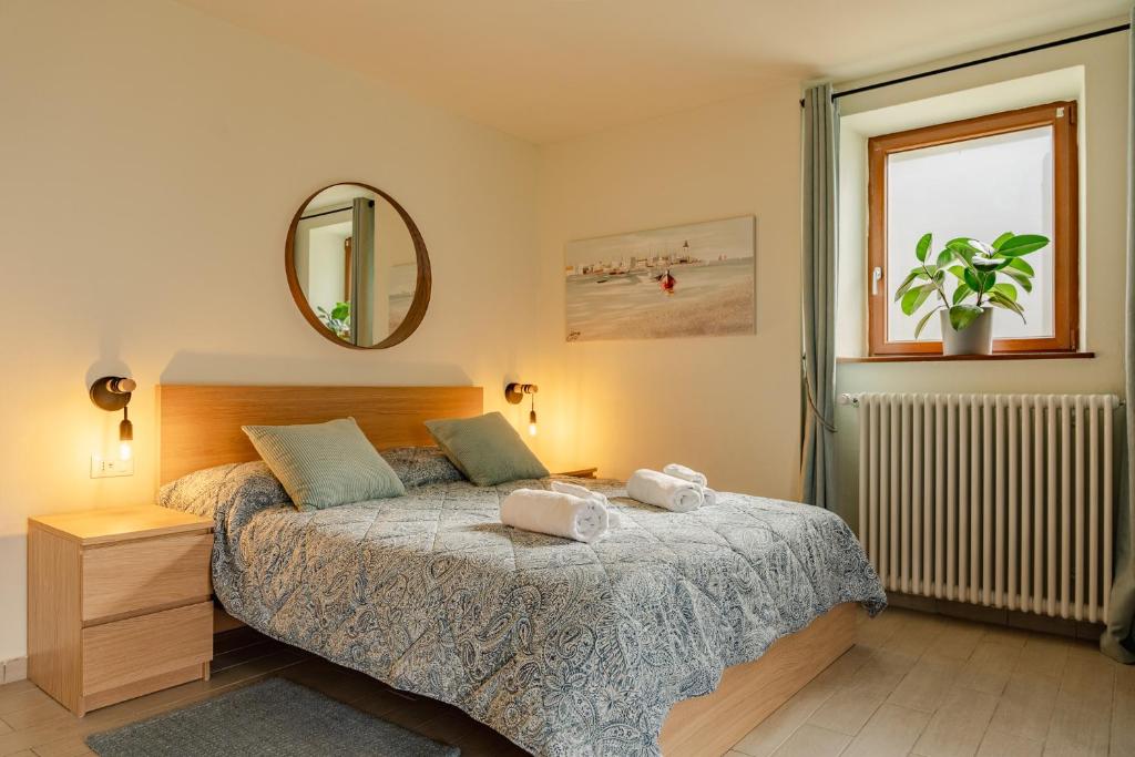 Schlafzimmer mit einem Bett, einem Spiegel und einem Fenster in der Unterkunft Casa Galya with private patio by GardaDoma in Brenzone sul Garda