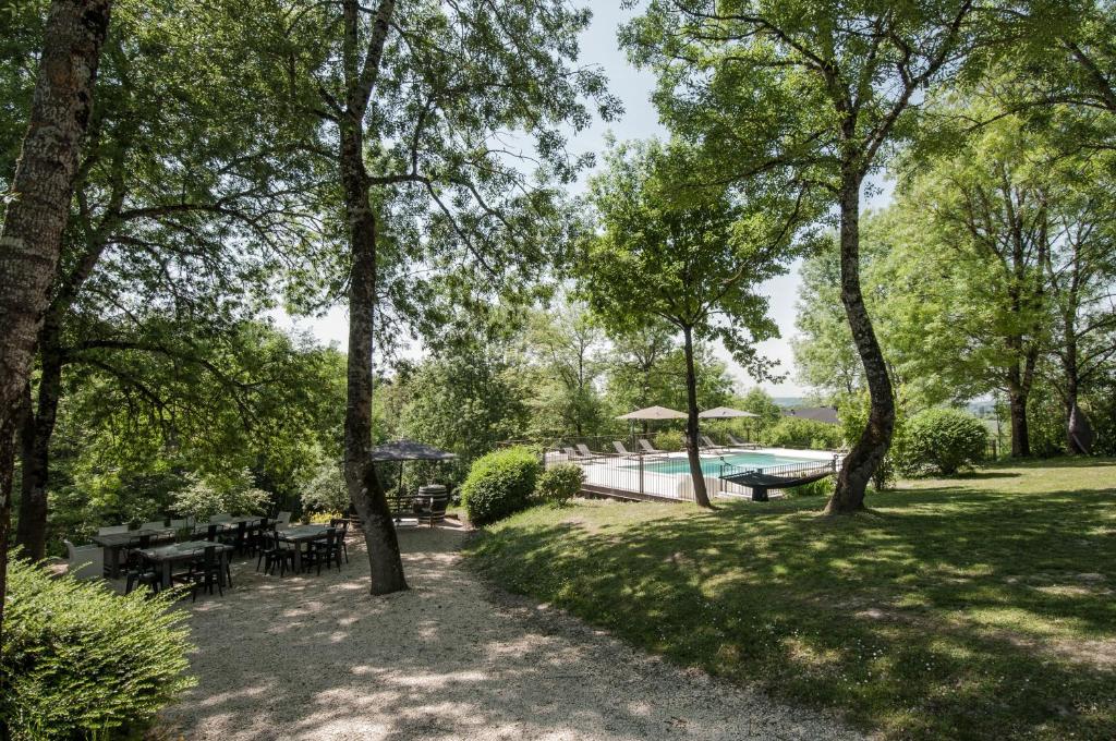 a yard with a swimming pool and tables and trees at Bassiviere Barn Chic in Saint-Étienne-de-Villeréal