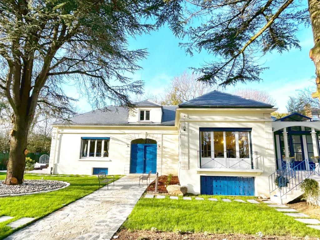 une maison blanche avec une porte bleue dans l'établissement Parismount, à Sceaux