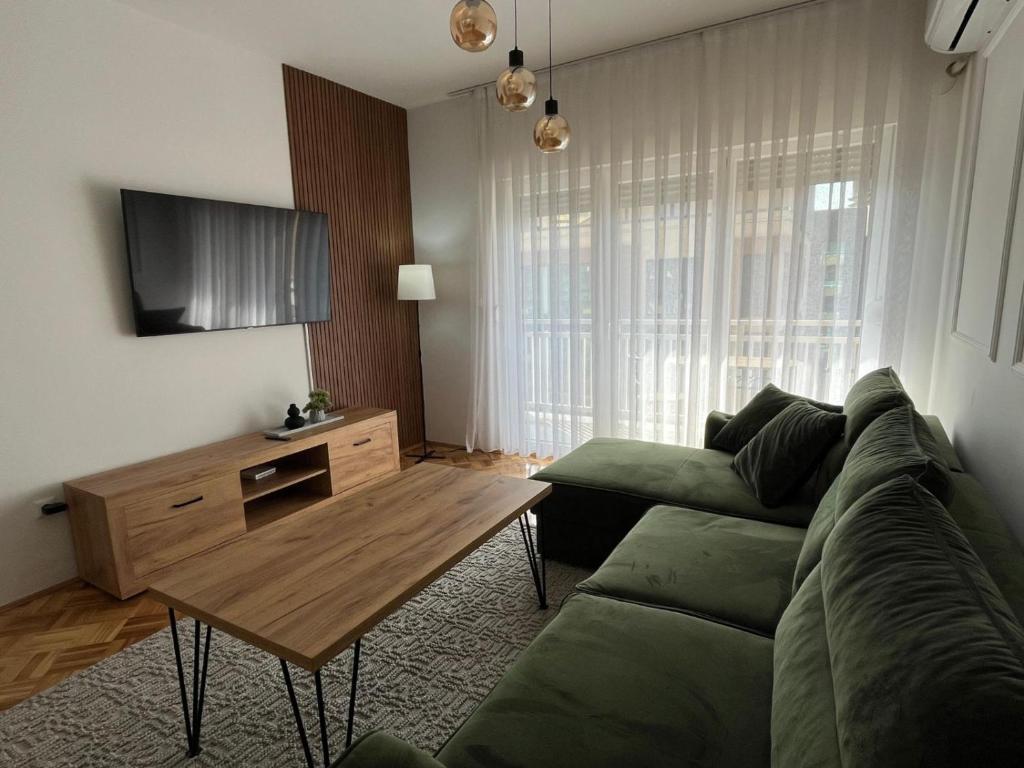 a living room with a green couch and a wooden table at ZARA Apartman Živinice in Živinice