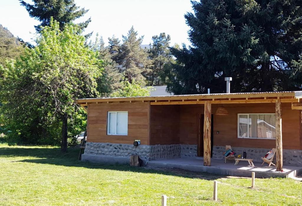 a log cabin with a porch in a yard at Alma de Puelo in Lago Puelo