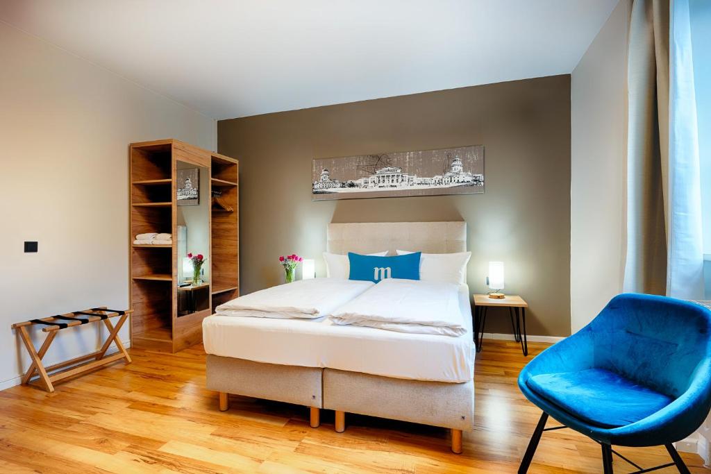 ein Schlafzimmer mit einem Bett und einem blauen Stuhl in der Unterkunft martas Hotel Berlin-Mitte in Berlin