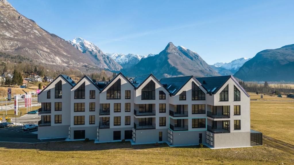 a large white building with mountains in the background at Apartments Svitnjak in Bovec