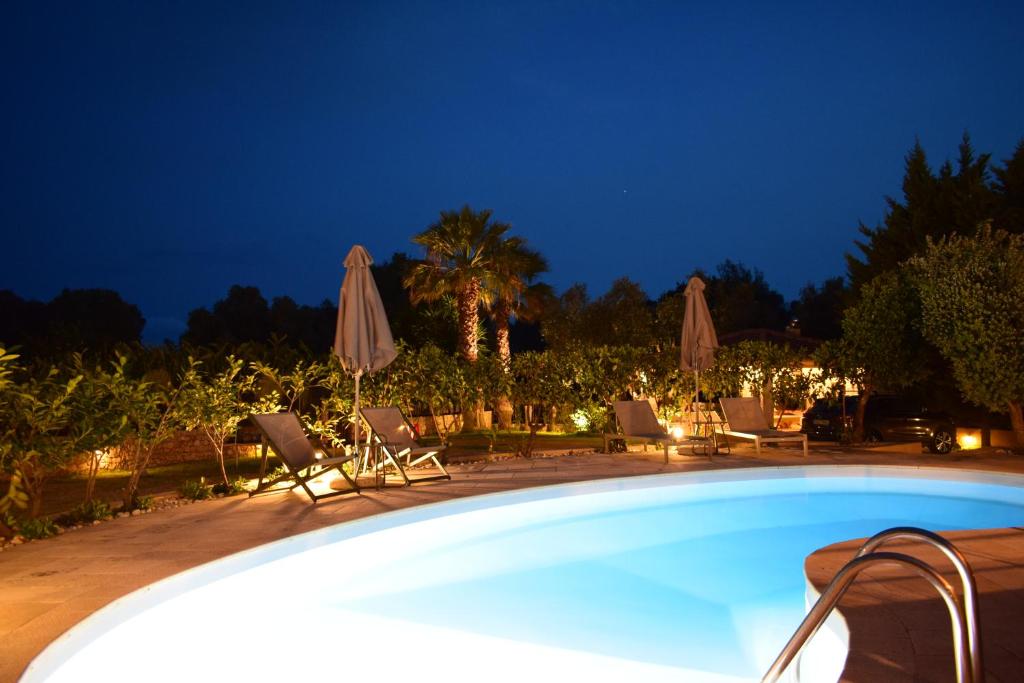 a swimming pool at night with chairs and umbrellas at Apeiron Villas - Olive Forest Apartment in Kefallonia