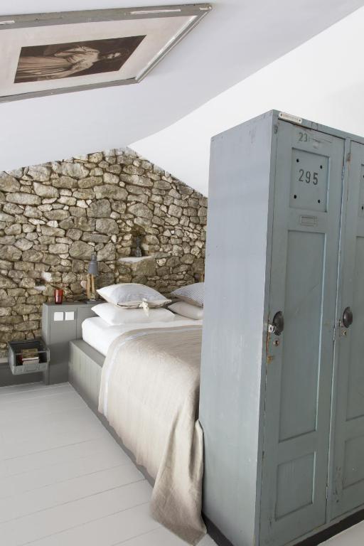 a bedroom with a bed and a stone wall at Bassiviere Barn Chic in Saint-Étienne-de-Villeréal