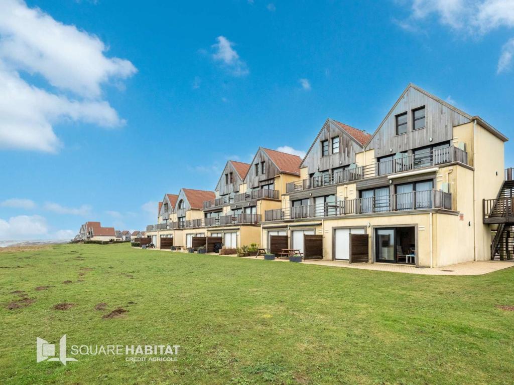 un grand bâtiment avec une pelouse devant lui dans l'établissement Appartement avec Terrasse et Parking Privatif, Proche Commerces - FR-1-675-28, à Wimereux