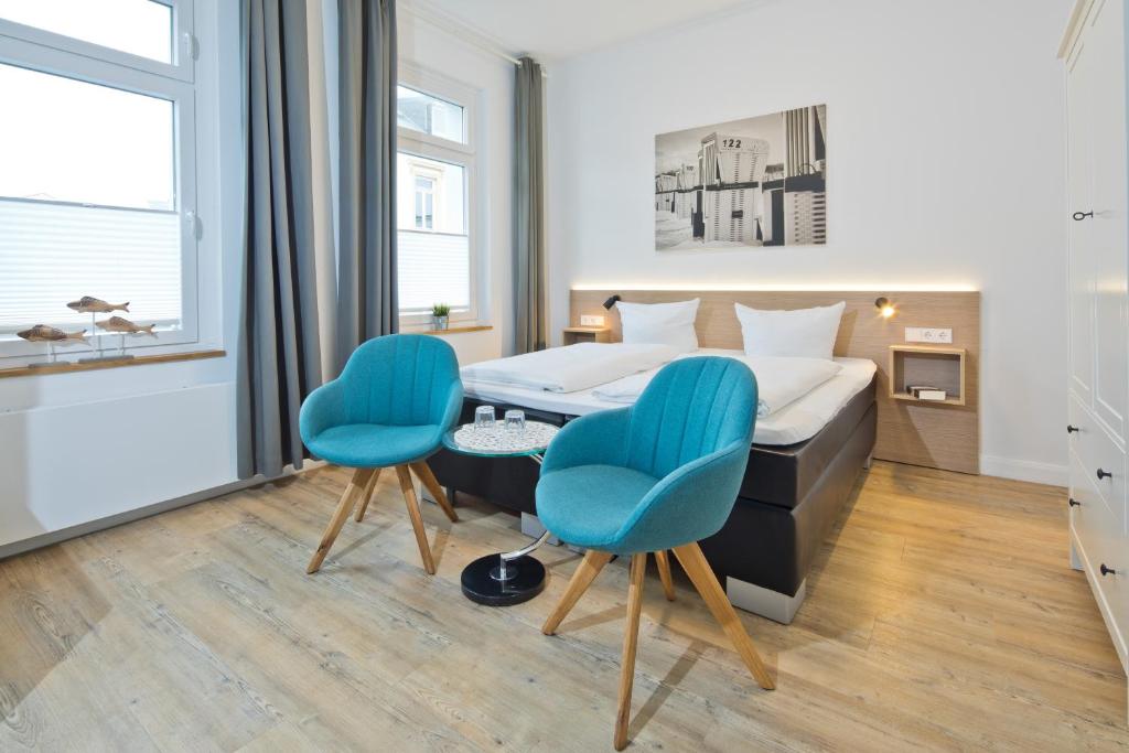 een slaapkamer met een bed en twee blauwe stoelen bij Haus Menno Janssen - Doppelzimmer in Norderney