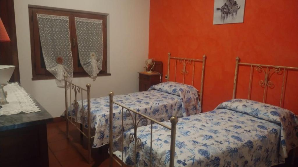 2 Betten in einem Zimmer mit orangefarbenen Wänden in der Unterkunft Casa vacanza Il Podere in Teulada