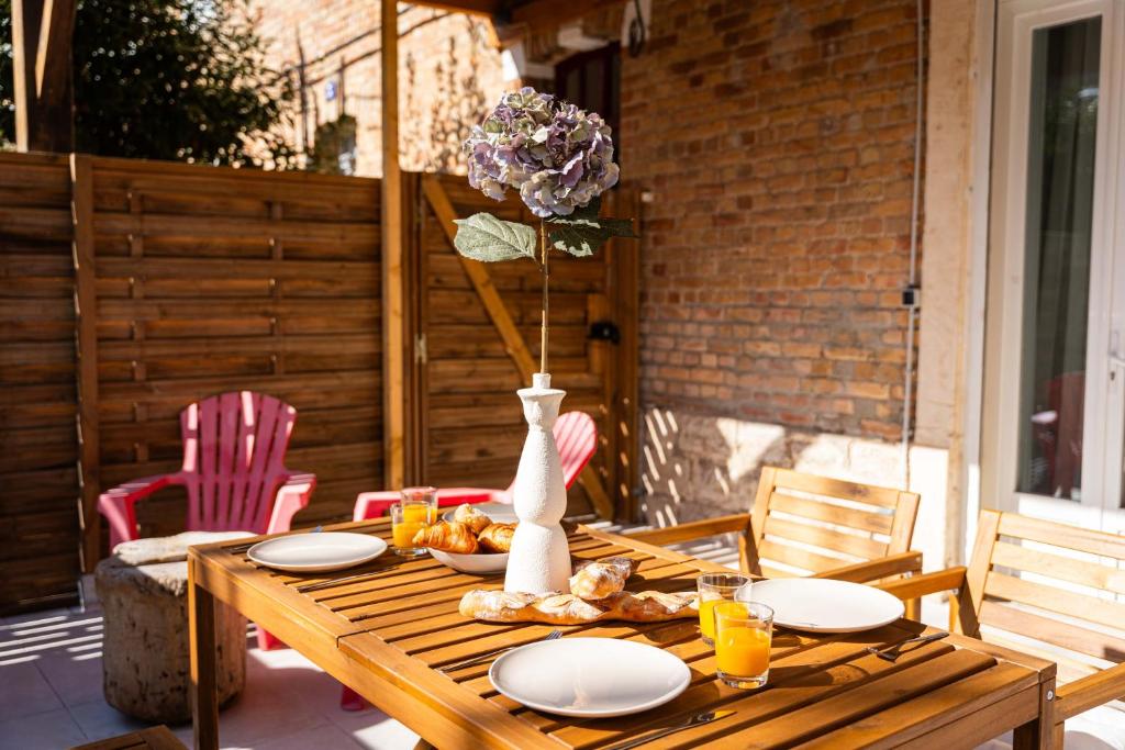 a wooden table with plates of food and a vase at Spacieux T2 au coeur de la Camargue - 10mn Plage in Salin-de-Giraud