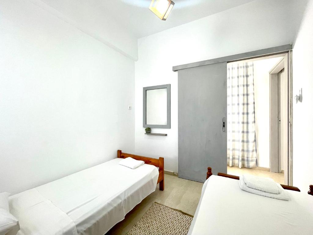 Duas camas num quarto branco com uma janela em Philoxenia traditional house em Palaiólimnos