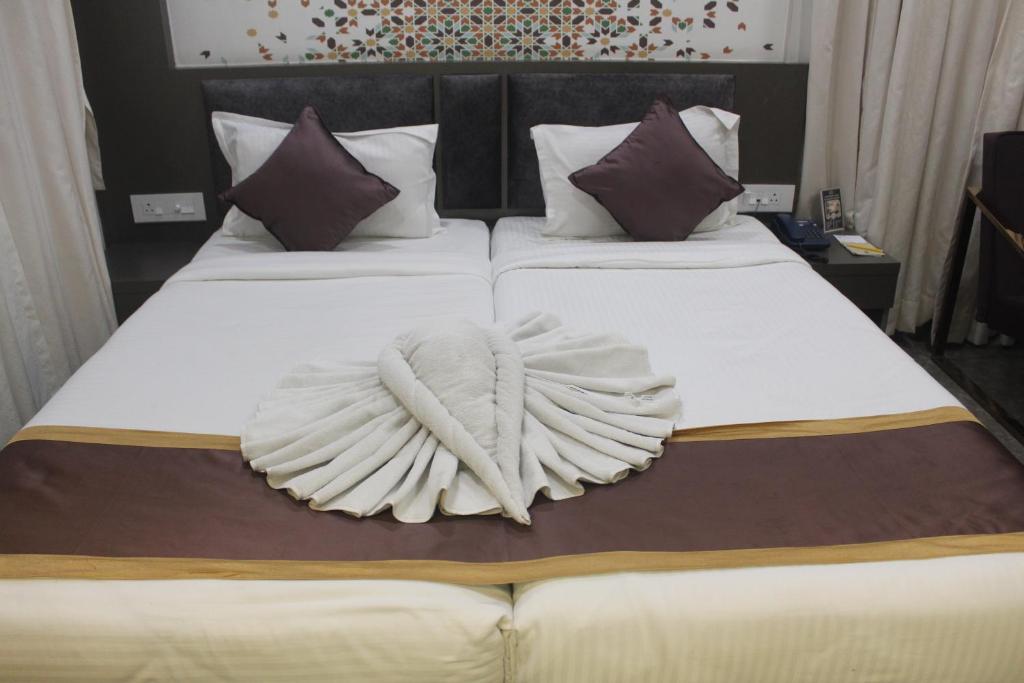 two beds with white sheets with wings on them at Continental Lodge & Continental Residency in Māldah