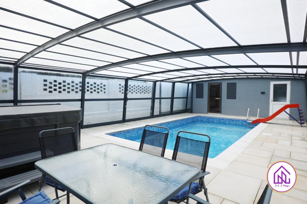 a swimming pool with a table and chairs in a building at Luxury House, Swimming Pool, Hot Tub, Sauna in Cardiff
